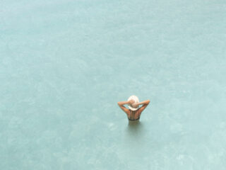 woman swimming in ocean surrounded by aqua blue water