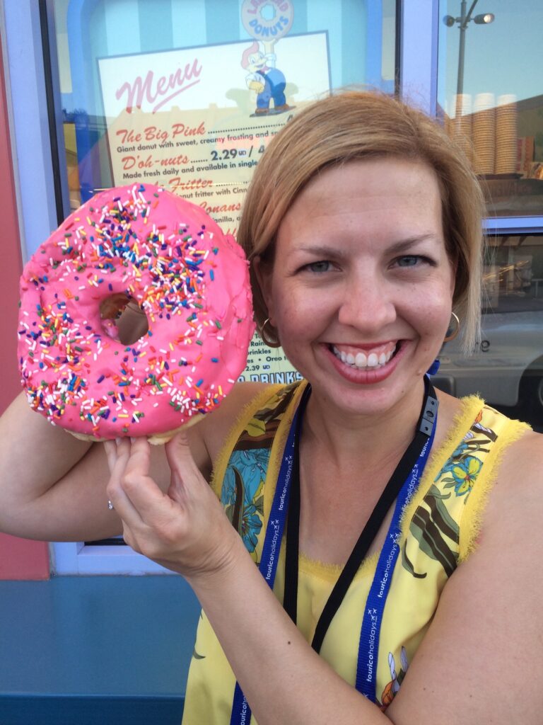 woman holding a giant pink donut that is as big as her head