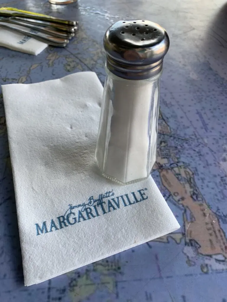 glass shaker of salt on white margaritaville napkin