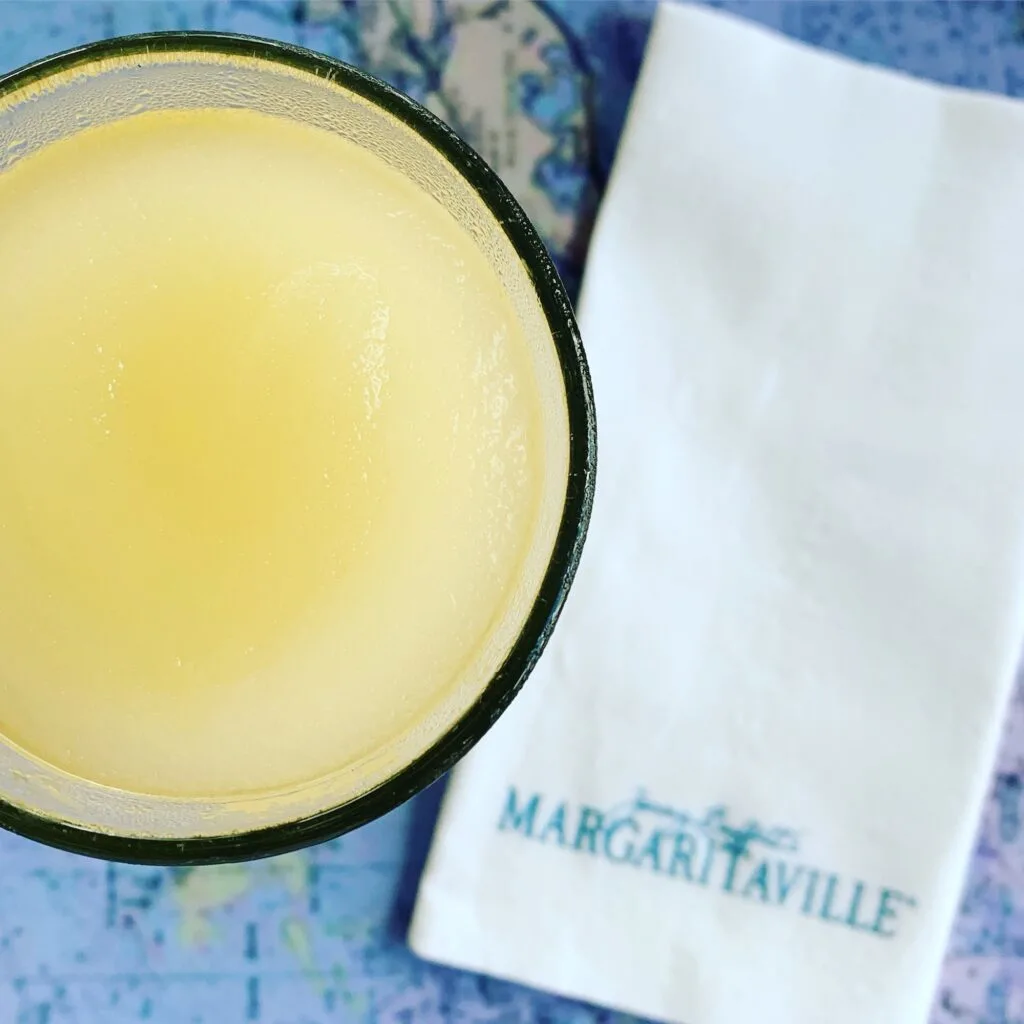 margarita in a glass with white margaritaville napkin beside it
