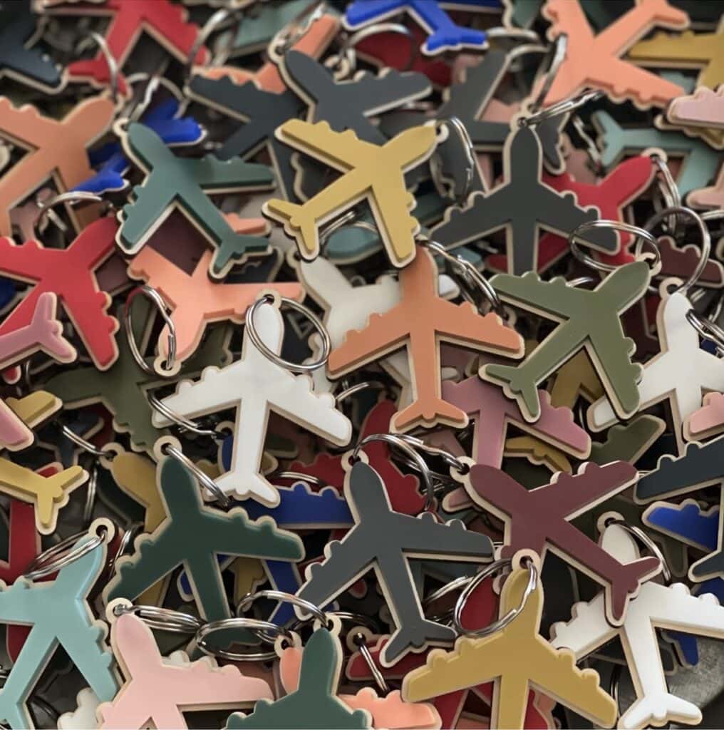 A pile of colorful airplane-shaped keychains overlapping each other, shown in various colors including green, white, red, and yellow&mdash;perfect as fun and practical flight attendant gifts.