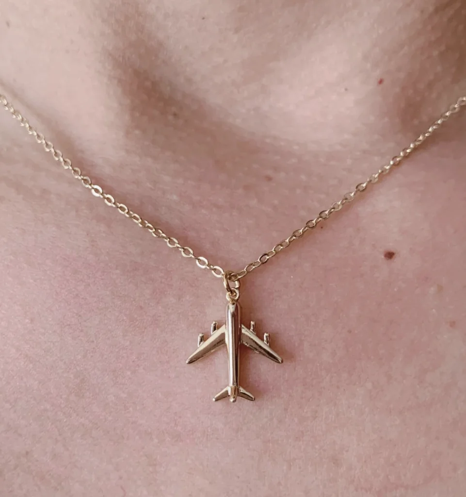 airplane necklace worn on a woman's neck
