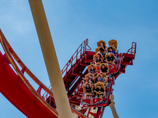 adults on a roller coaster with blue sky in the background