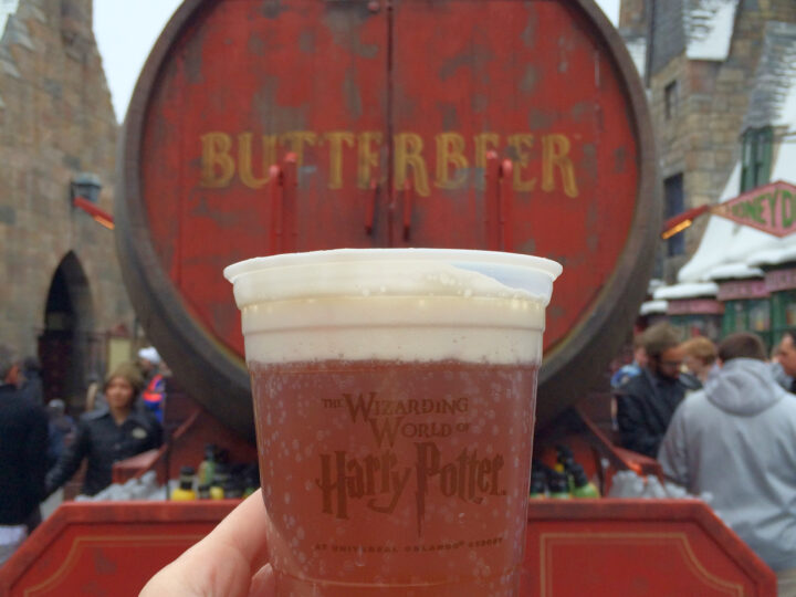 holding a cup of butterbeer in front of a barrel in Harry Potter land