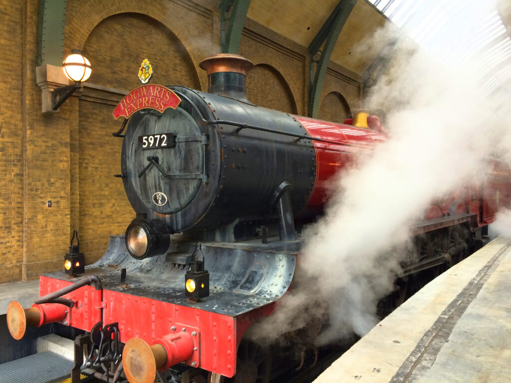 Hogwarts express train in station with steam coming from engine