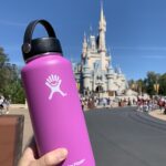 holding a hydro flask water bottle in front of Magic Kingdom Castle in Disney World