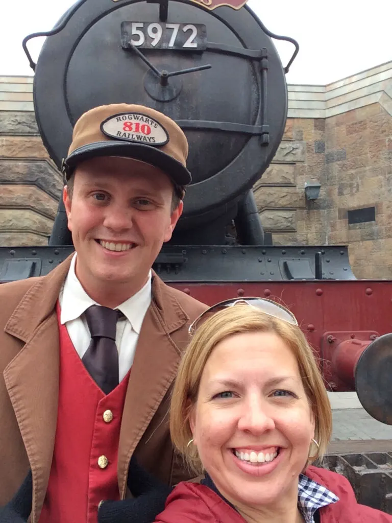 woman with Hogwarts express railroad conductor in front of the train