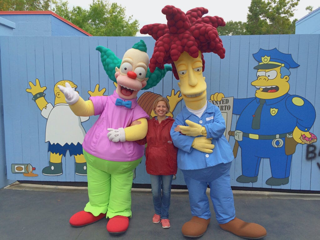 woman standing with Simpsons characters wearing big shoes at Universal Studios