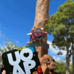 holding a universal Orlando annual pass in front of tower sign at Islands of Adventure theme park