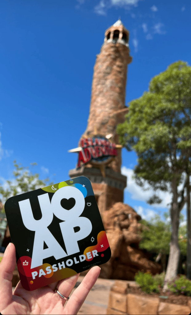 holding a universal Orlando annual pass in front of tower sign at Islands of Adventure theme park
