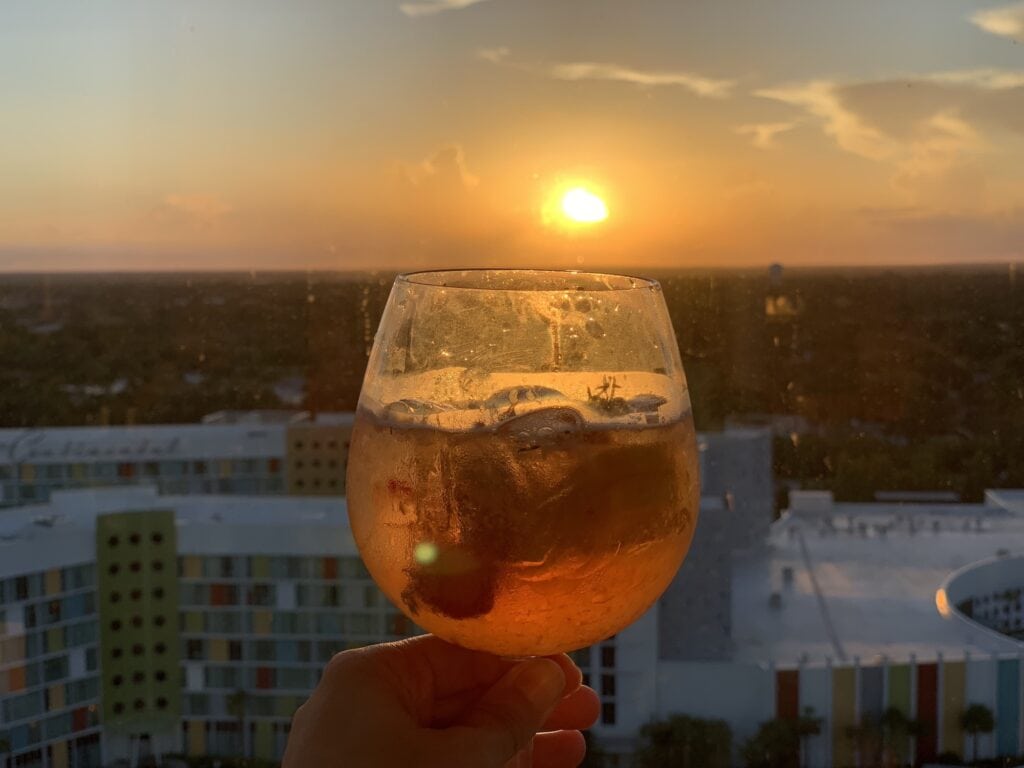 cocktail in a glass held up in front of a setting sun at Universal Studios