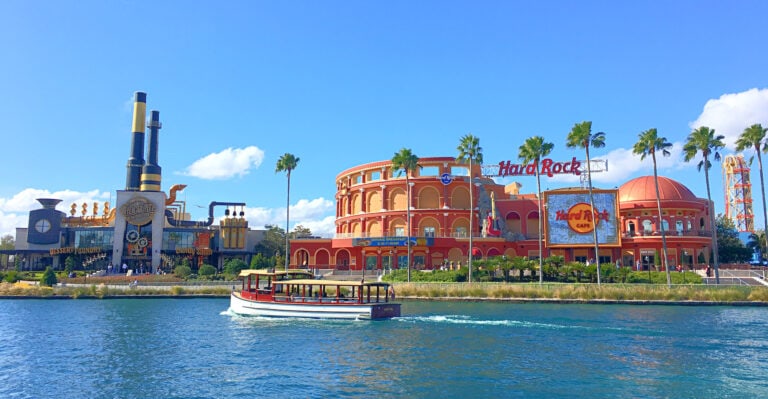 Hard Rock Cafe and Toothsome Chocolate Factory restaurants seen across the lagoon at Universal CityWalk with a boat taxi floating by