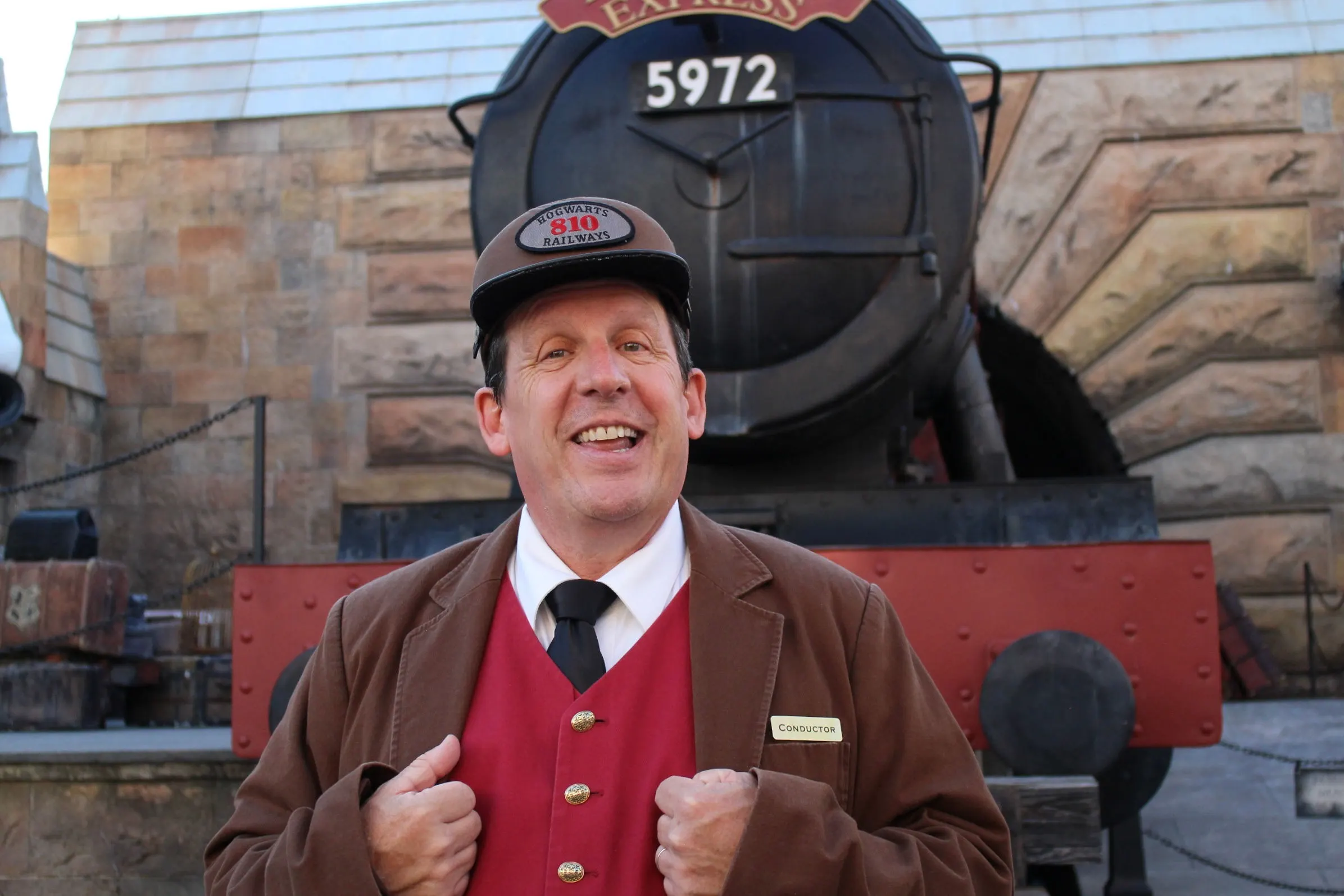 conductor of Hogwarts express in front of train at wizarding world of Harry Potter