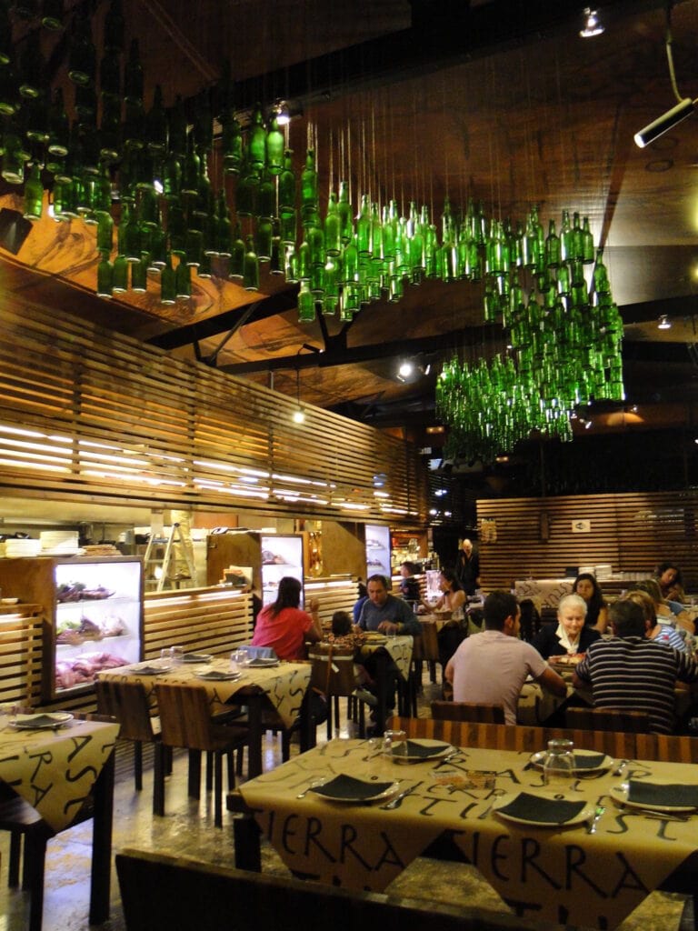 A Spanish restaurant in Asturias with a unique décor of lush green bottles hanging from the ceiling.
