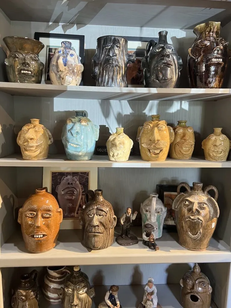 A shelf full of vases with faces on them, perfect for unique souvenirs in Asheboro.