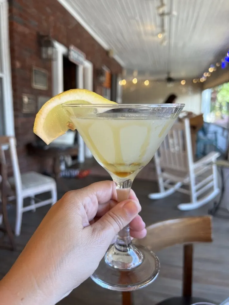 A person enjoying The Henderson while holding a martini on a porch.
