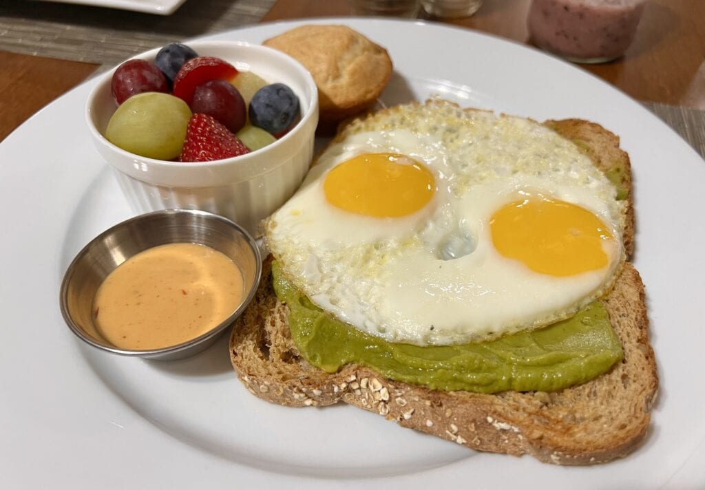 A plate of toast with eggs and fruit on it, also known as The Henderson.