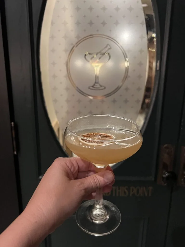 A person holding a cocktail in front of a door, enjoying one of the many things to do in Asheboro.